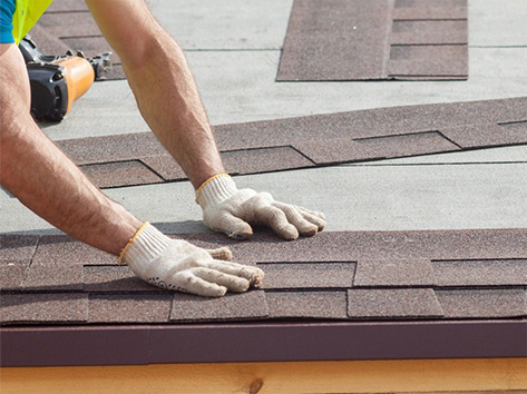 A man installing shingles on a roof.