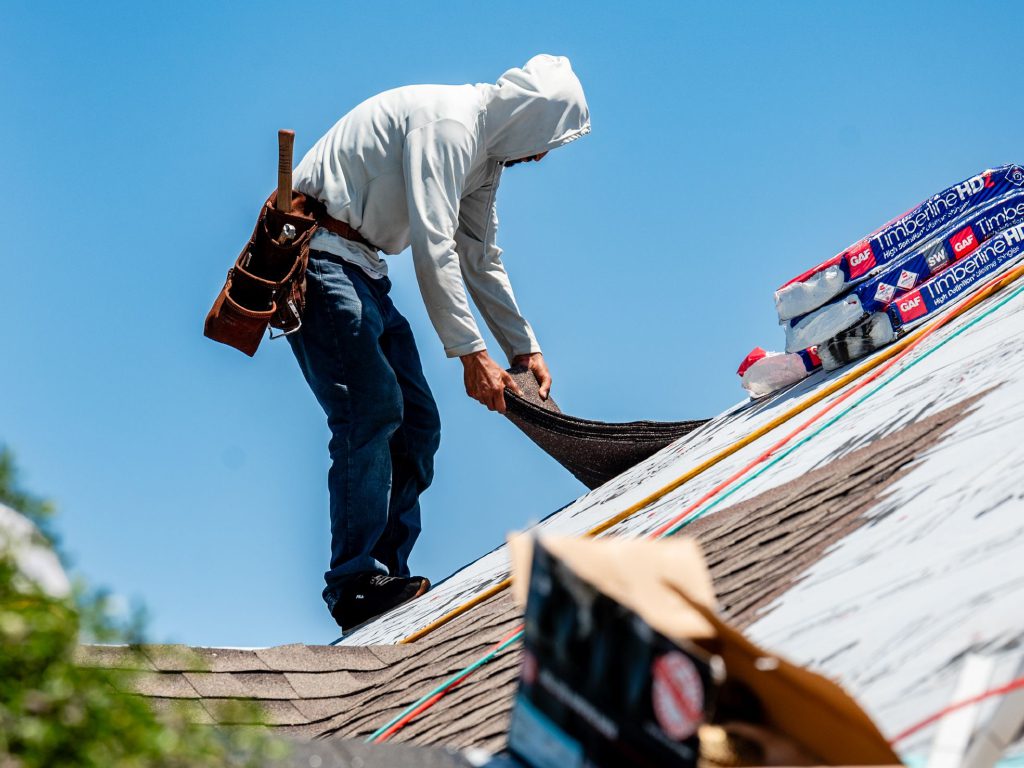 A man installing shingles on a roof.