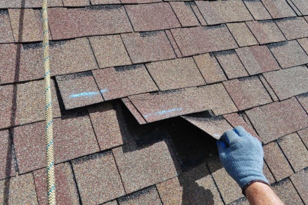 A person removing shingles from a roof.